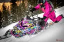 Kim Onasch in all pink gear riding a Polaris Axys snowmobile wrapped in her signature pink design