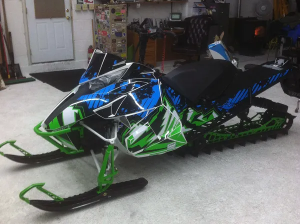 A Arctic Cat Proclimb snowmobile with a blue, green, and black grunge mountain Altitude custom vinyl wrap.