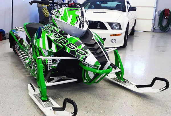 A Arctic Cat Procross snowmobile with a white, green, and black stripes Arc Reactor custom vinyl wrap.