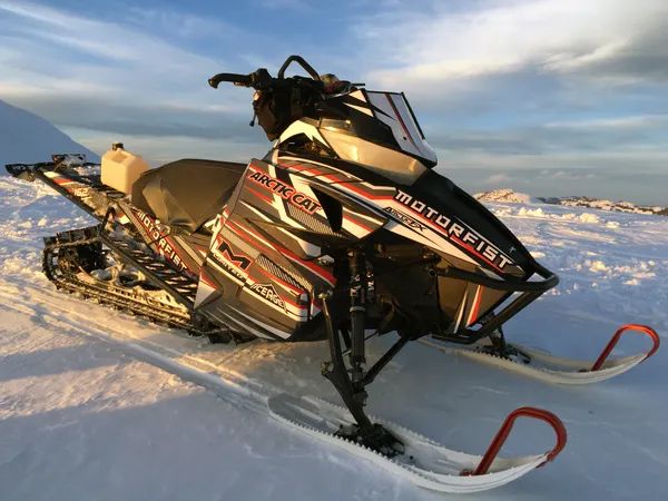 A Arctic Cat Procross snowmobile with a red, white and black stripes Bred2Win custom vinyl wrap.