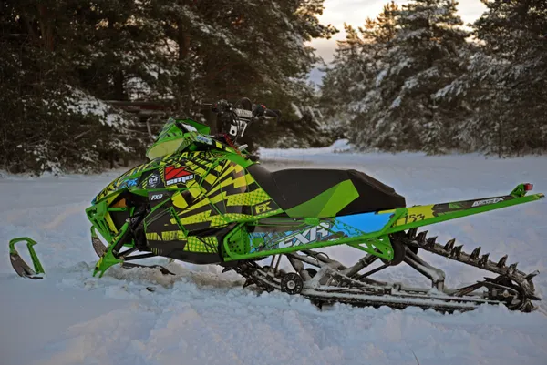 A Arctic Cat Proclimb snowmobile with a green, yellow and red grunge halftone Delirious custom vinyl wrap.