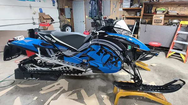 A Arctic Cat Procross snowmobile with a blue, black, and white Fox Rebound custom vinyl wrap.