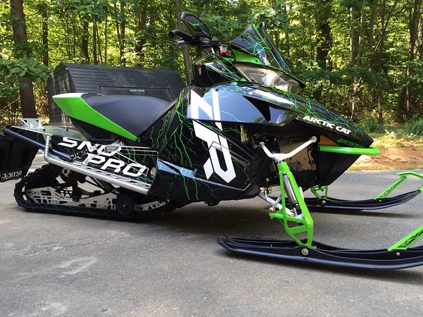 A Arctic Cat Procross snowmobile with a green, white and black lightning Shock Treatment custom vinyl wrap.