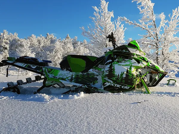 A Arctic Cat Procross snowmobile with a white, green, and black trees Sub Zero custom vinyl wrap.