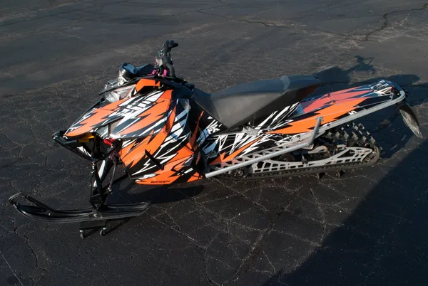 A Arctic Cat Procross snowmobile with a orange, white and black lightning Bolts and Wings custom vinyl wrap.