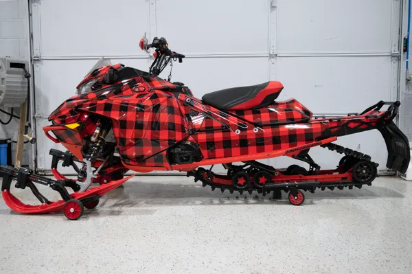 A Lynx snowmobile with a red and black Plaid pattern custom vinyl wrap with stock logos added.