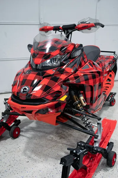 A Lynx snowmobile with a red and black Plaid pattern custom vinyl wrap with stock logos added.