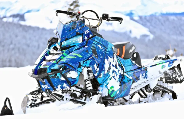 A Polaris Axys Mountain snowmobile with a lime green, black, and blue grunge star Wartorn custom vinyl wrap.
