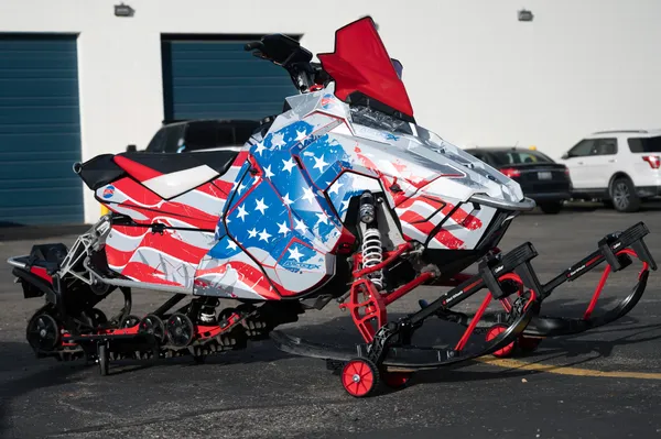 A Polaris Axys Trail snowmobile with a gray, red, white, and blue American Flag custom vinyl wrap.