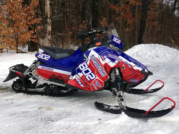 A Polaris Axys Trail snowmobile with a red, white, and blue Entz Frontier custom vinyl wrap.