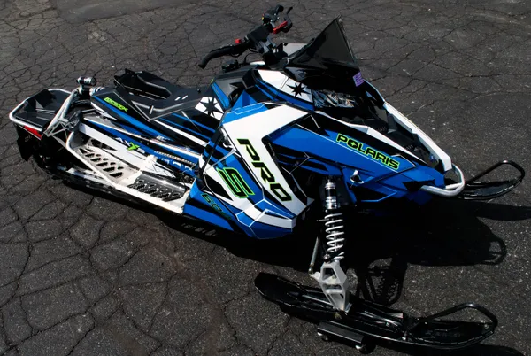 A Polaris Axys Trail snowmobile with a black, white, lime, and blue racing stripes Relay custom vinyl wrap.