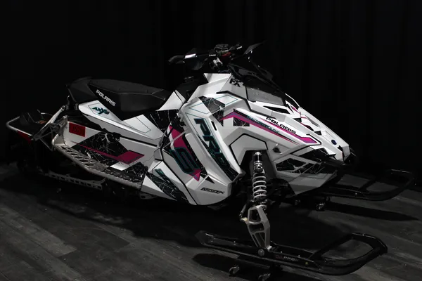 A Polaris Axys Trail snowmobile with a black, white, and pink grunge Rogue custom vinyl wrap.