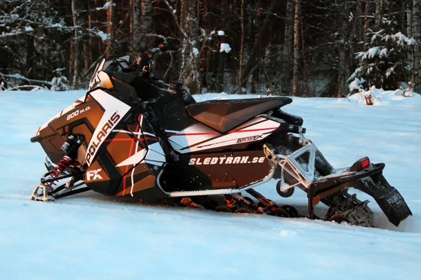A Polaris Axys Trail snowmobile with a black, white, and red Sledtrax custom vinyl wrap.