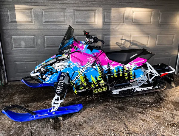 A Polaris Axys Trail snowmobile with a black, blue, and lime squeeze Sub Zero custom vinyl wrap.