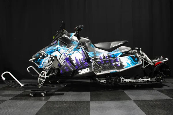 A Polaris Axys Trail snowmobile with a black, blue, and purple Sub Zero custom vinyl wrap.