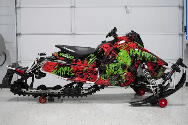 A Polaris Axys Trail snowmobile with a black, red, and lime graffiti Tagged custom vinyl wrap.