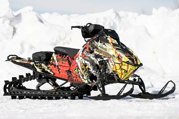 A Polaris Matryx Mountain snowmobile with a lime squeeze, red, black, and white Adams Inversion custom vinyl wrap.