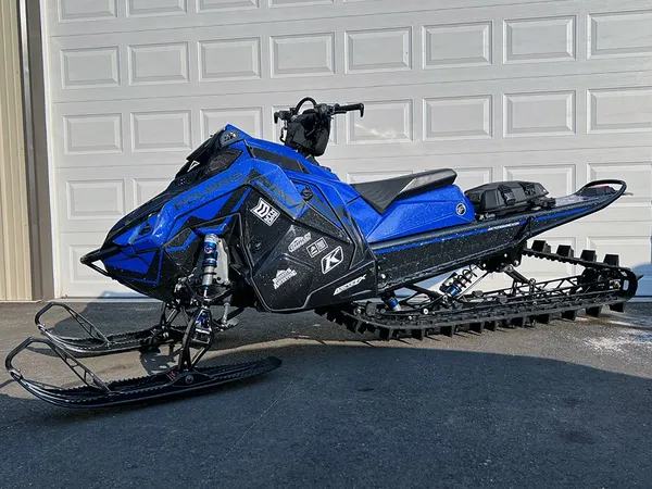 A Polaris Matryx Mountain snowmobile with a blue and black Burandt Incognito custom vinyl wrap.