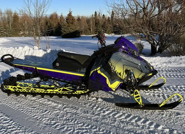 A Polaris Matryx Mountain snowmobile with a lime squeeze, purple, and black Entz Elevate custom vinyl wrap.