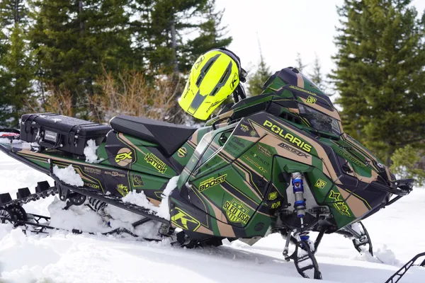 A Polaris Matryx Mountain snowmobile with a black, tan, and lime squeeze Sled USA Inertia custom vinyl wrap.