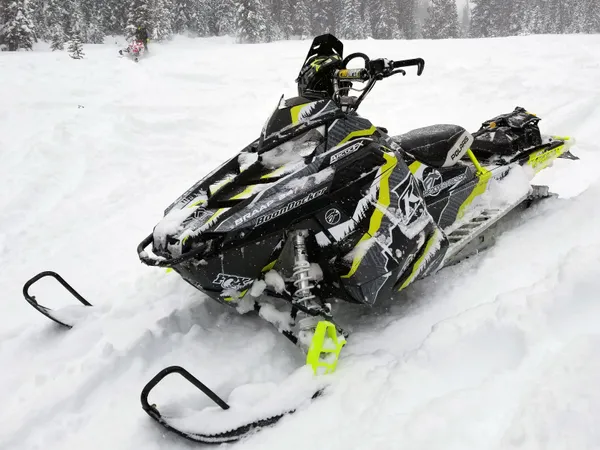 A Polaris Pro-Ride snowmobile with a lime squeeze, black, and white Adams Alpine custom vinyl wrap.