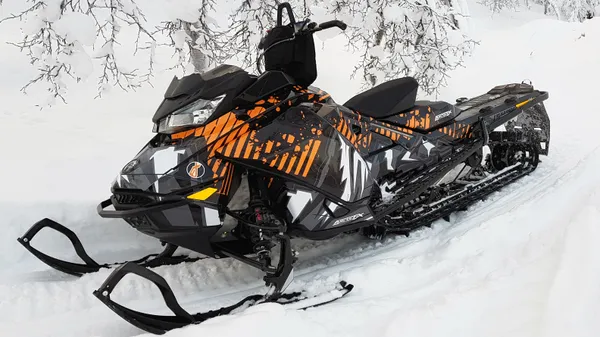 A Ski-Doo Gen4 Narrow Body snowmobile with a orange, white, and black mountain Altitude custom vinyl wrap.