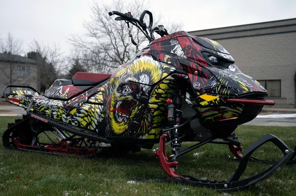 A Ski-Doo Gen5 Mountain snowmobile with a chrome, red, black, and lime squeeze Leif Alvarsson Tree Slayer custom vinyl wrap.
