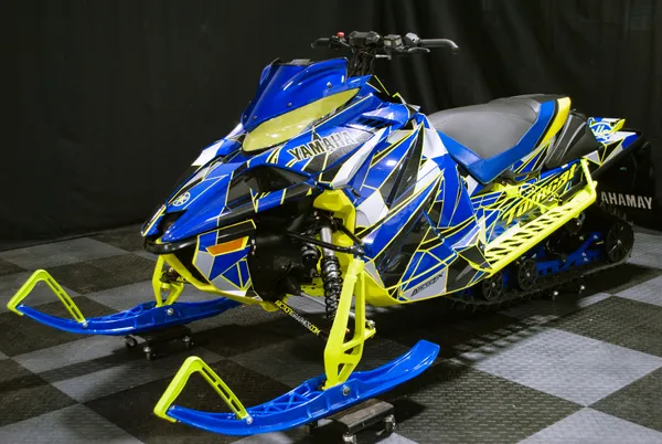 A Yamaha Sidewinder snowmobile with a blue, black, and lime squeeze Ascension custom vinyl wrap.